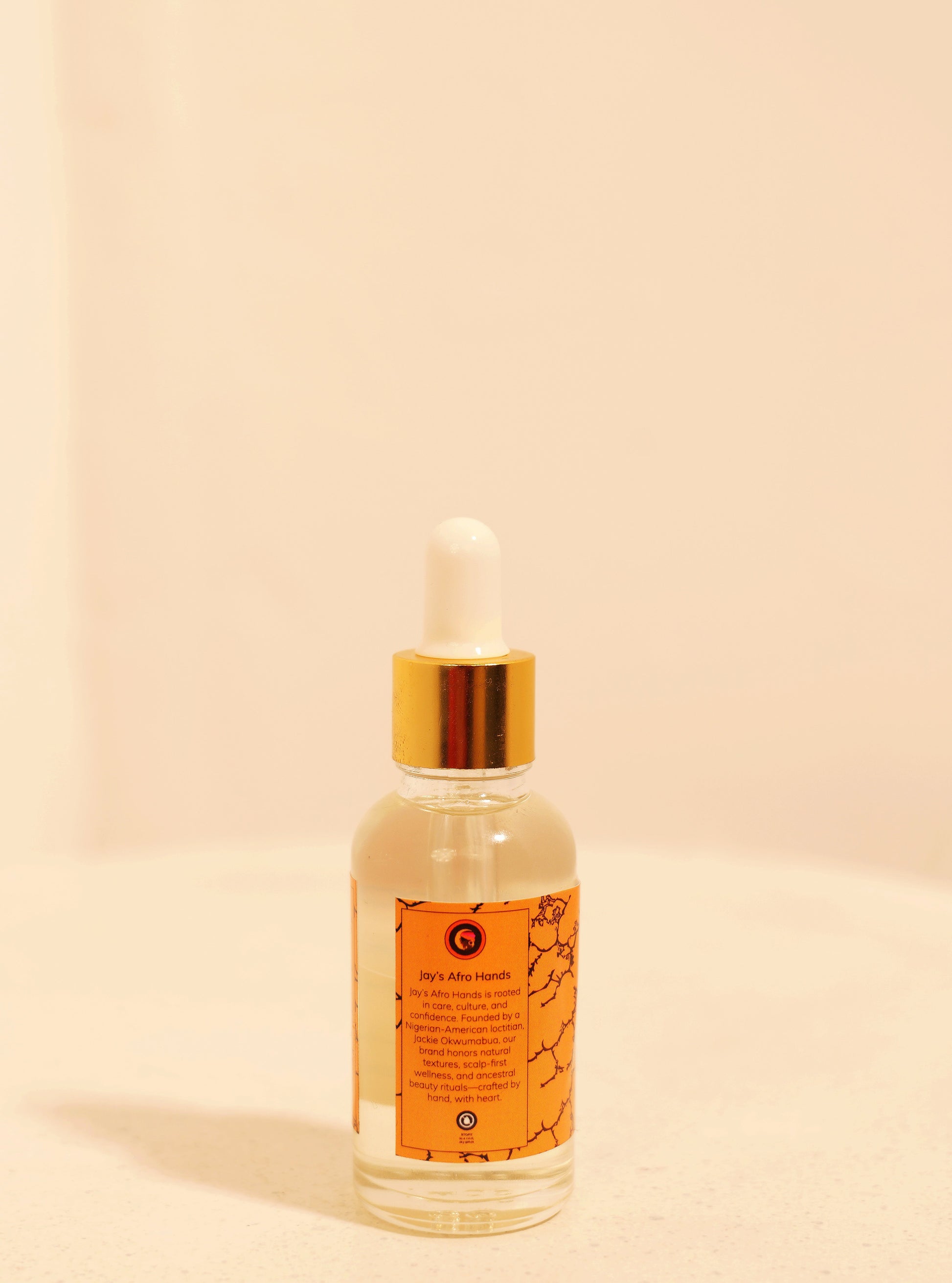 Clear bottle with gold cap on a beige background