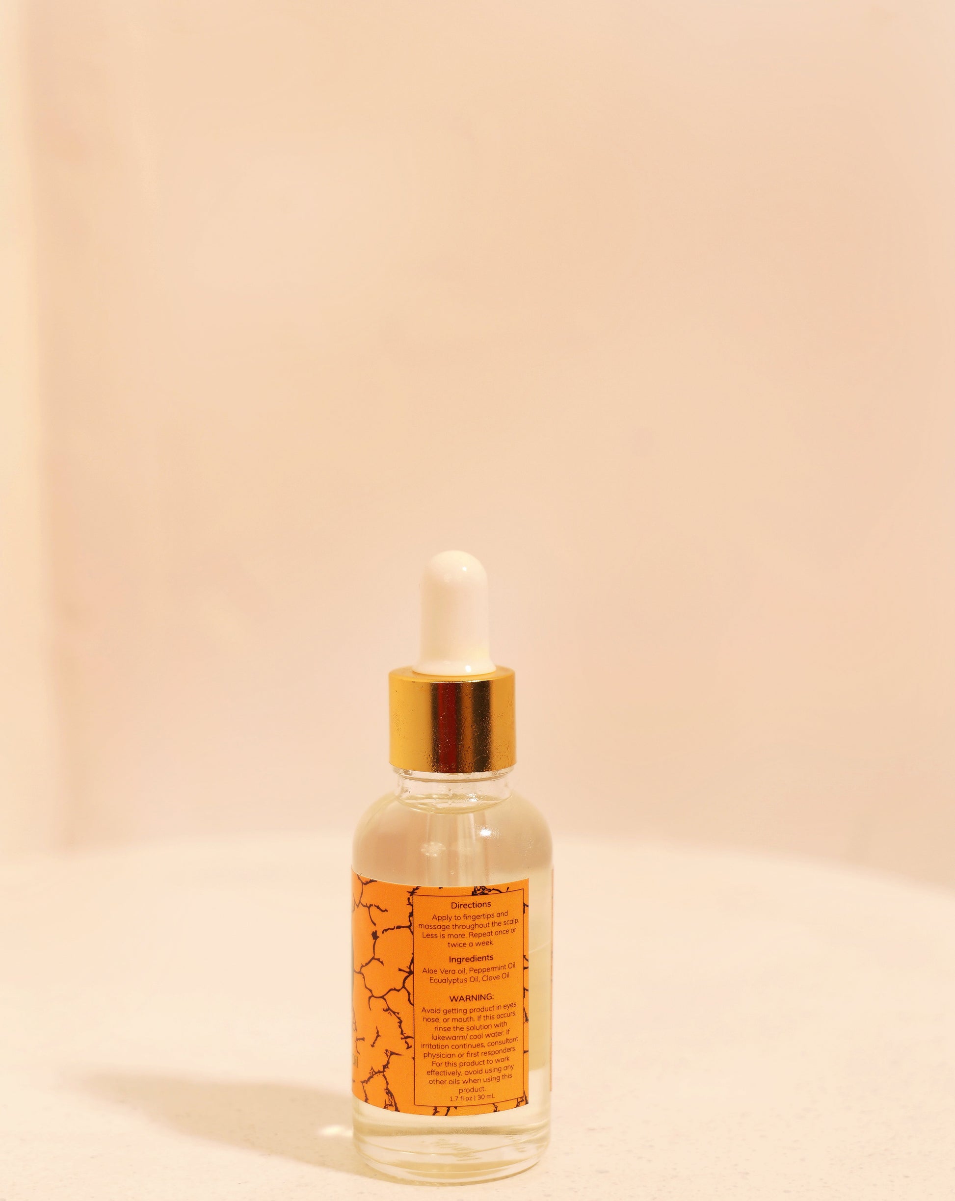 Skincare dropper bottle with orange label on a beige background