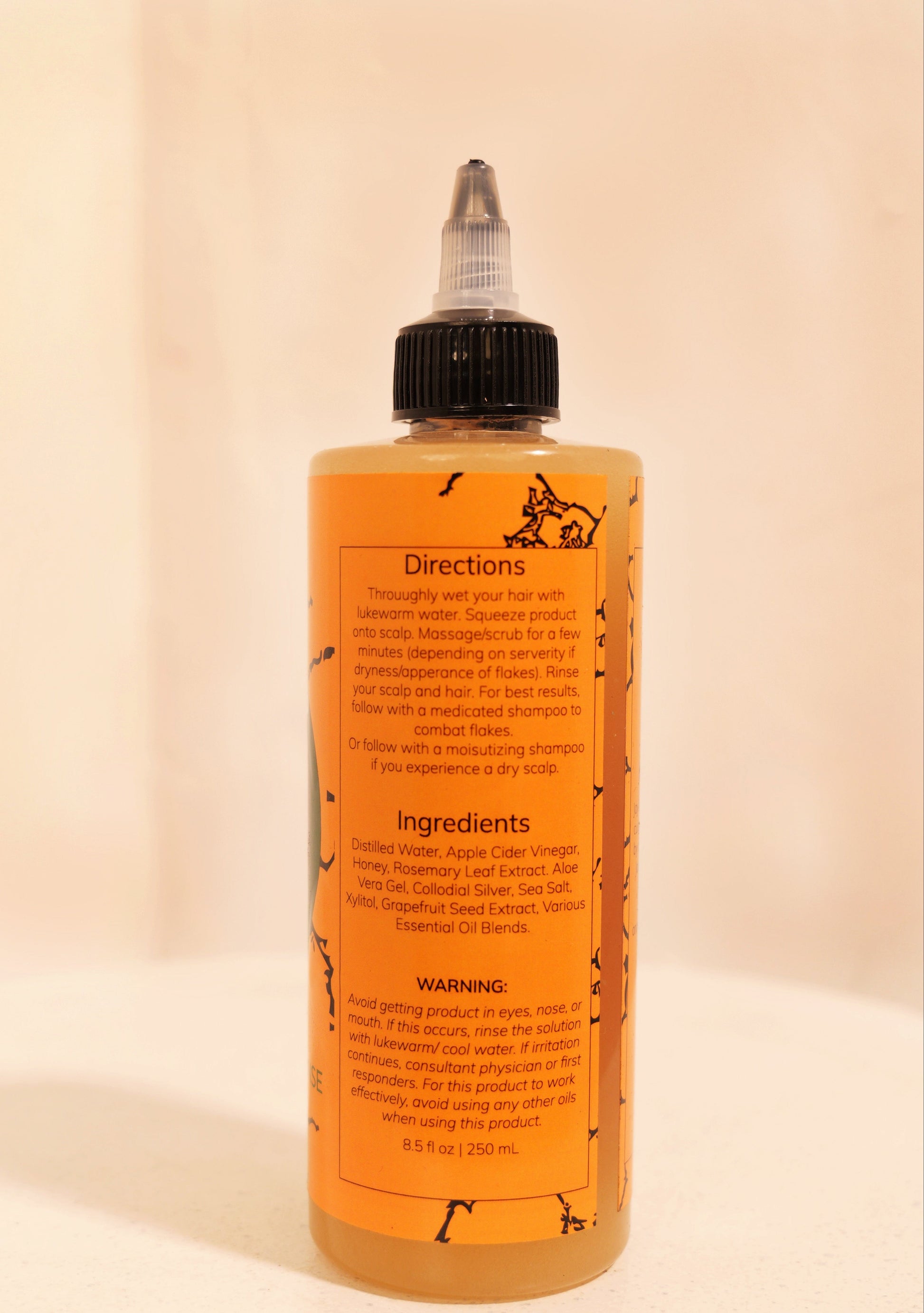 Bottle of hair product with orange label on a beige background
