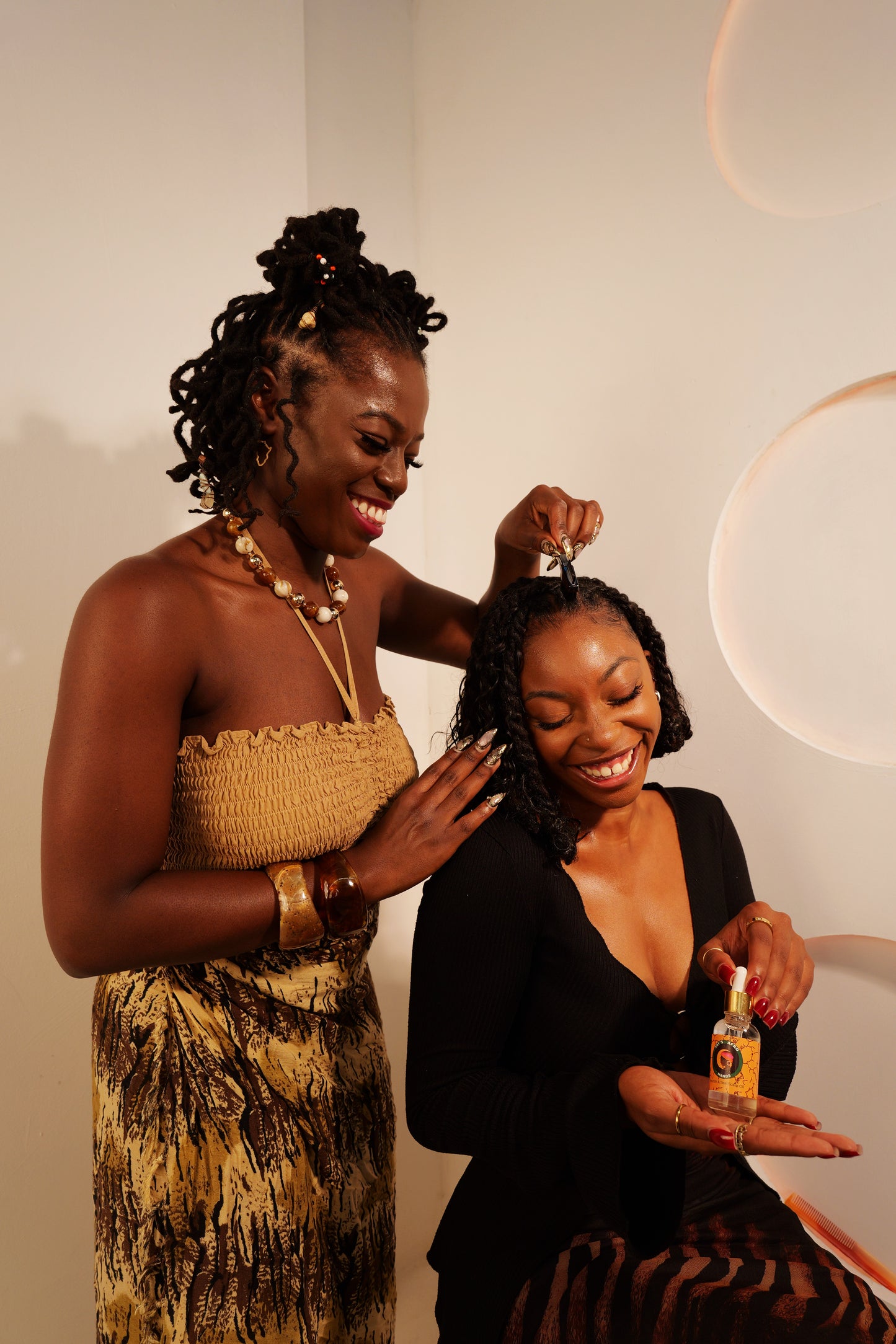 Two women interacting with a bottle of hair product against a neutral background