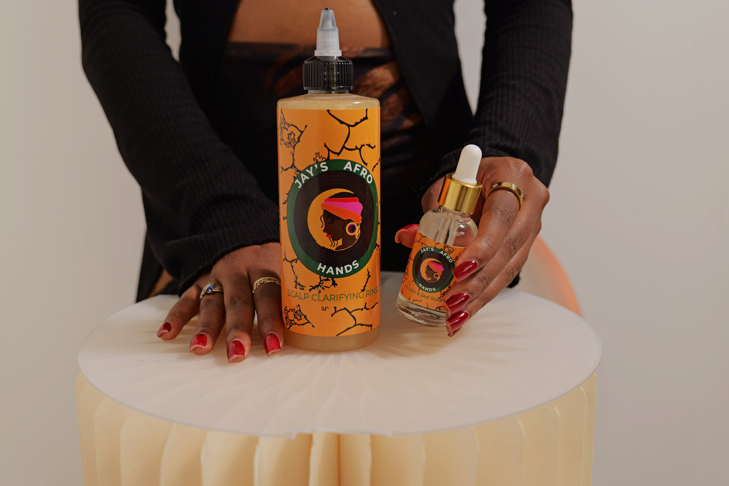 Two bottles of Jay's Afro Hands' products on a white surface with a neutral background