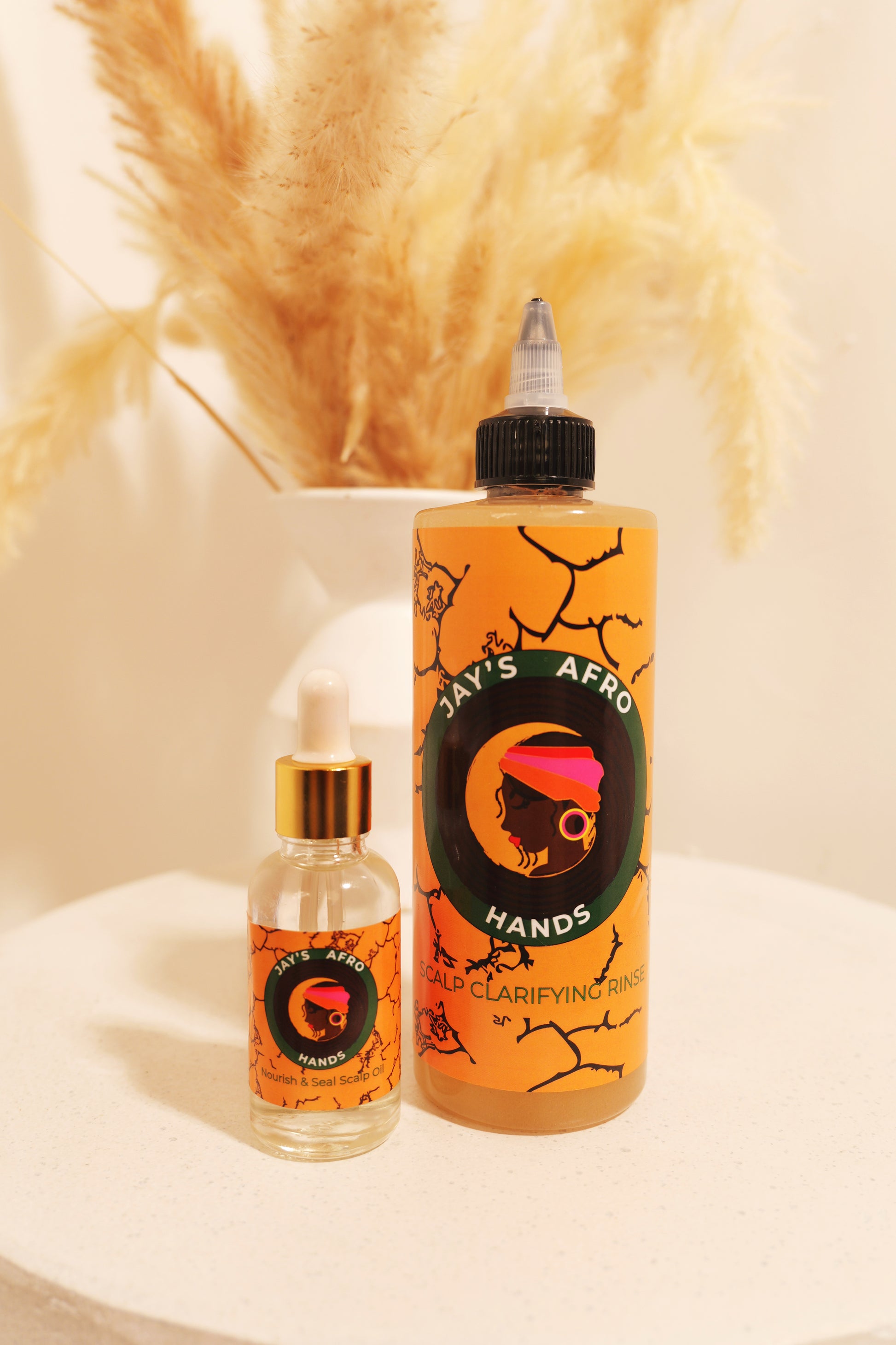 Two bottles of 'Jay's Afro Hands' hair care products on a white surface with a blurred background.